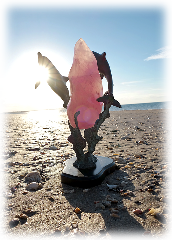 about lumeurias - rose quartz and dolphins statue on a shelley beach